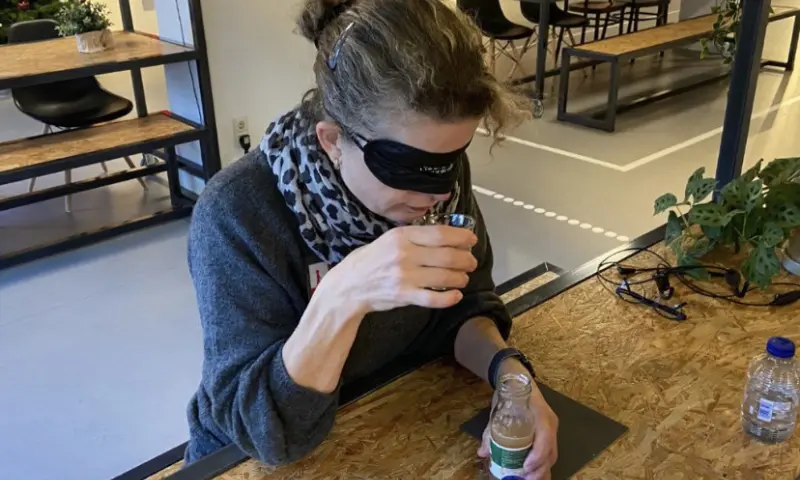 Vrouw ruikt aan het drinken om te raden wat het is.