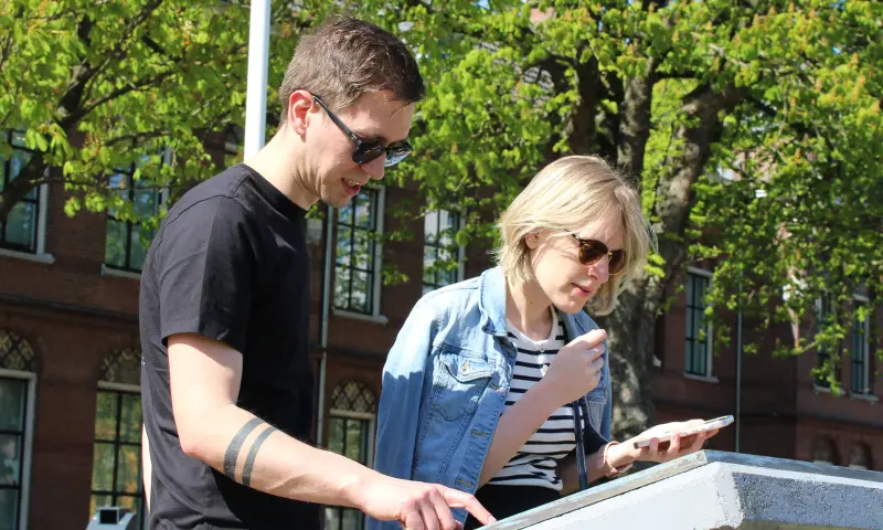 Spelers zoeken aanwijzing in citygame City Detective van Qugato