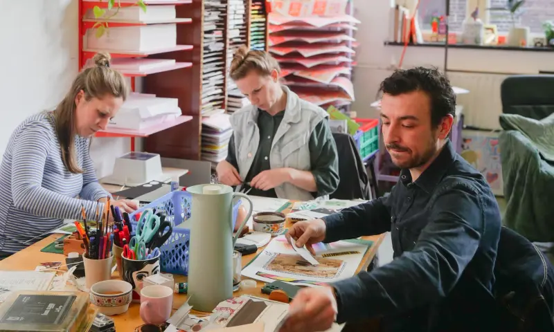 Mensen aan een tafel die aan het werk zijn met een collage